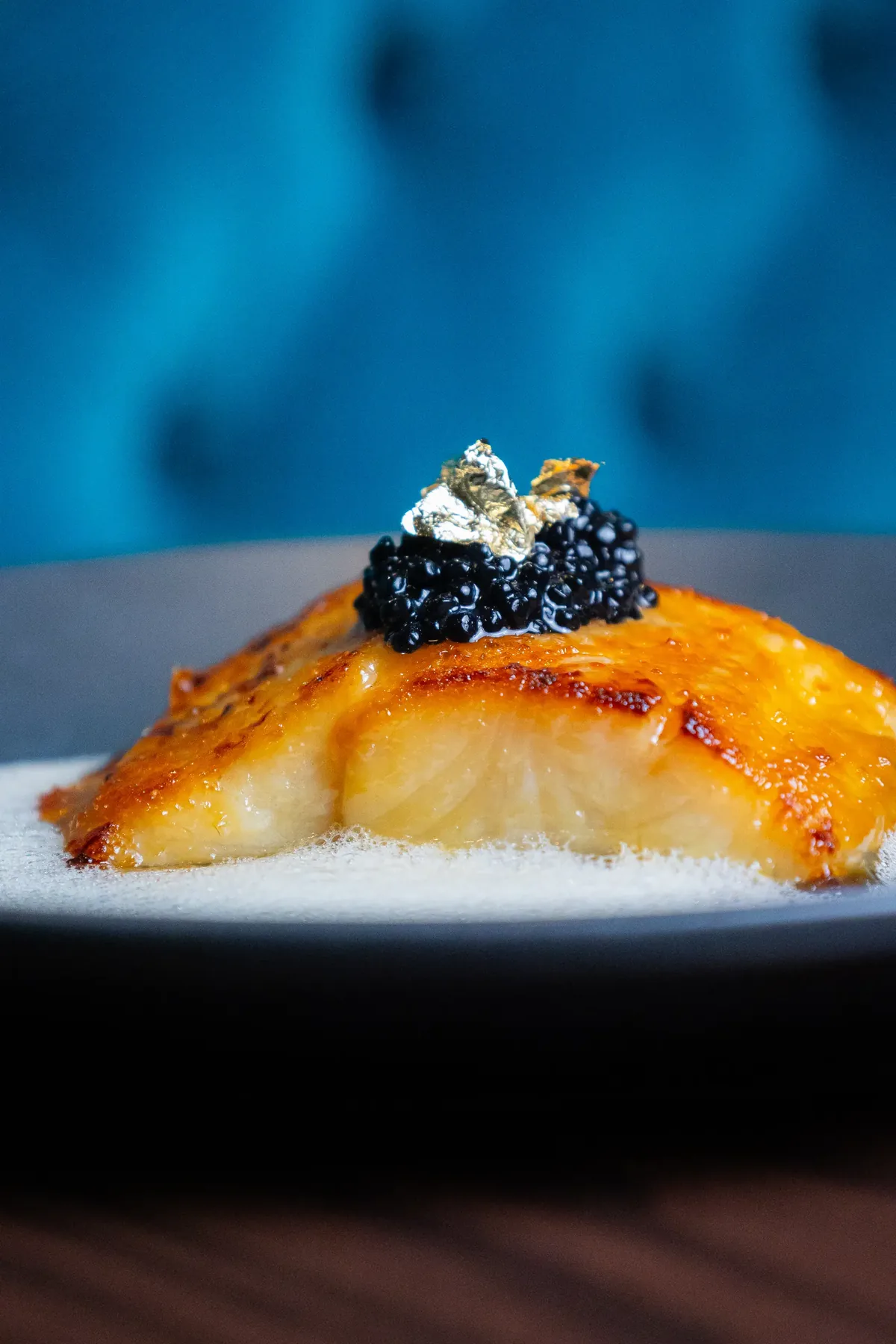 Glazed fish topped with caviar, against blue velvet